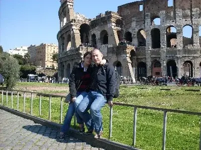 Caterina e Matteo seduti su una ringhiera davanti al Colosseo, a Roma