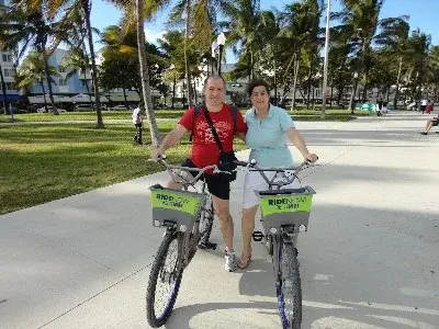 Caterina e Matteo in bicicletta su un viale costeggiato di palme