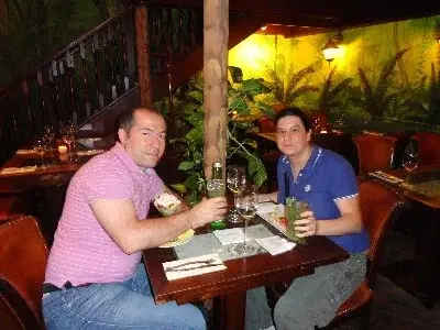 Caterina e Matteo brindano a cena in un ristorante dall'ambientazione tropicale